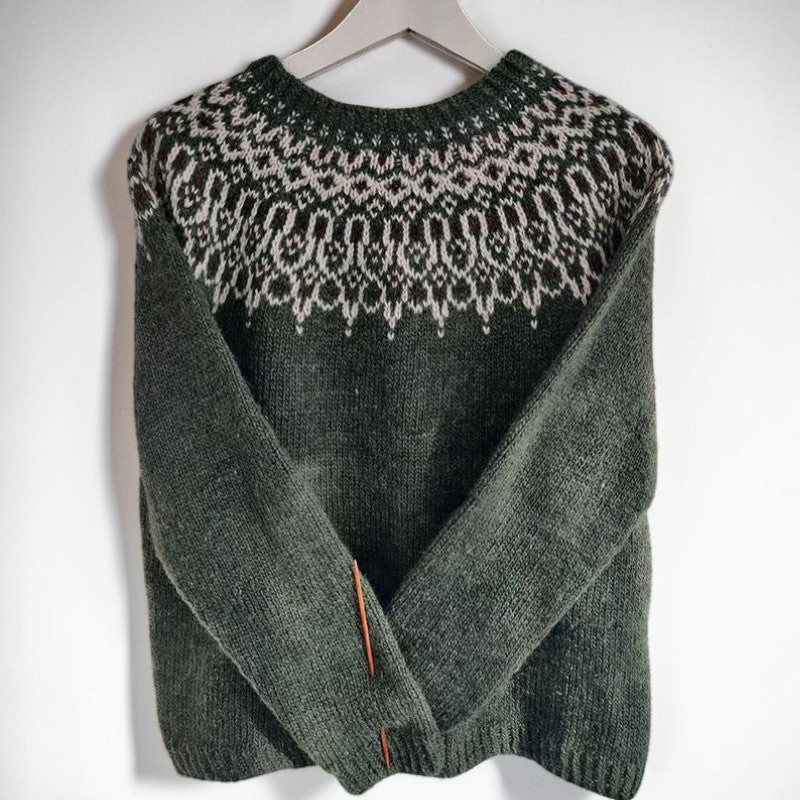 Vivian &amp; Cole Fara dark green jacquard sweater with intricate cream patterned yoke hanging on a tree in the snow