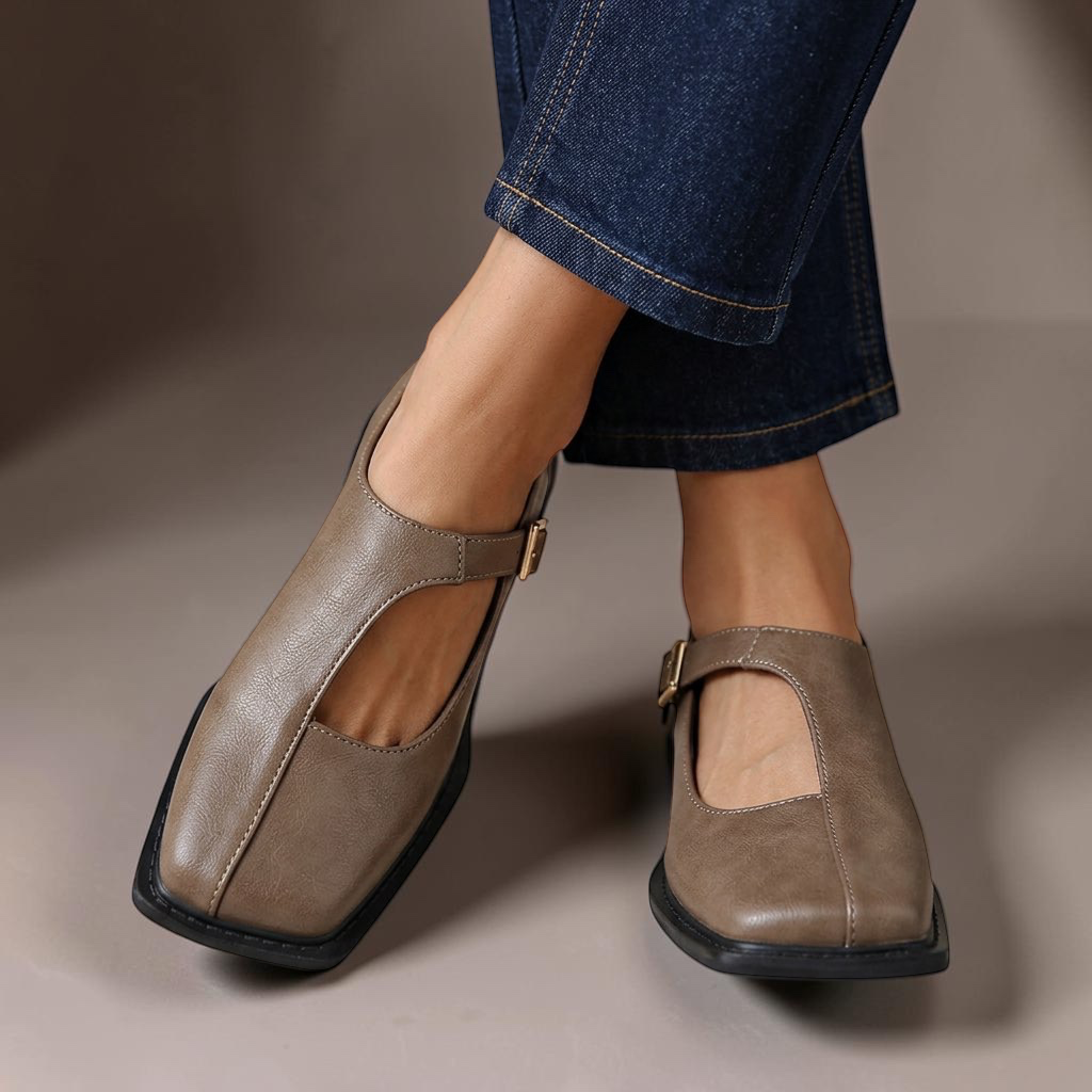 Vivian & Cole Rosalie ash gray leather-look flats with a classic T-strap design and square toe worn with blue jeans.