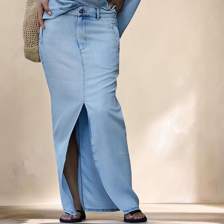 Vivian & Cole light wash denim maxi skirt with a high front slit and structured fit worn with black sandals
