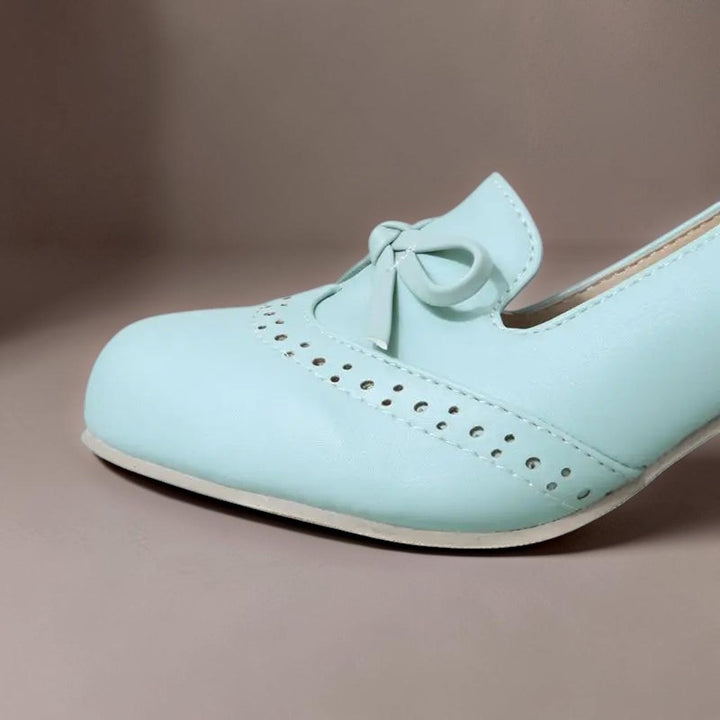 Vivian &amp; Cole Adelaide light blue slip-on pump with a decorative bow and perforated brogue detailing on the toe