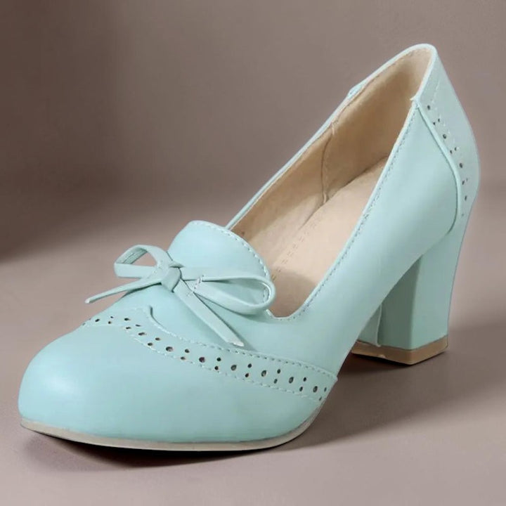 Vivian &amp; Cole Adelaide blue bow slip-on pumps with a manageable block heel and decorative brogue-style detailing.