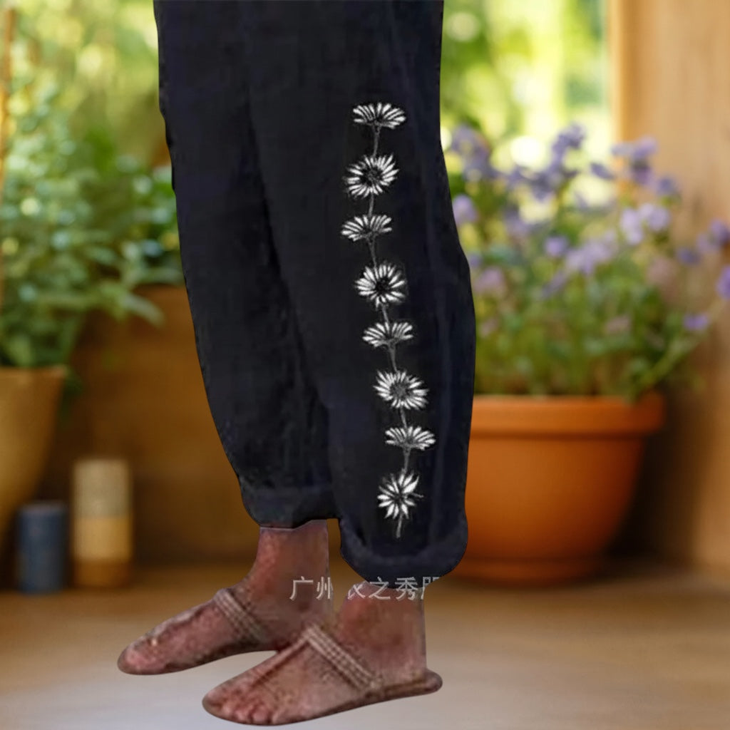 Vivian &amp; Cole black loose trousers with a side floral daisy print and elastic waist. Linen-feel fabric.