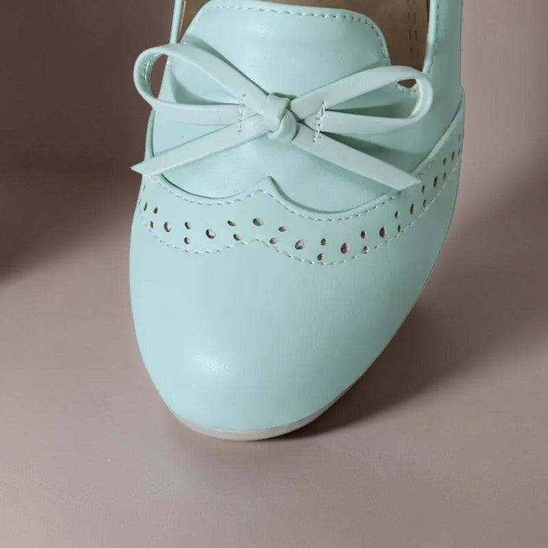 Vivian &amp; Cole Adelaide light blue slip-on pump featuring a decorative bow and delicate brogue-style perforations