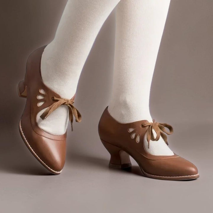 Vivian &amp; Cole brown vintage-style lace-up Mary Jane pumps with a rounded toe and low block heel worn with white tights