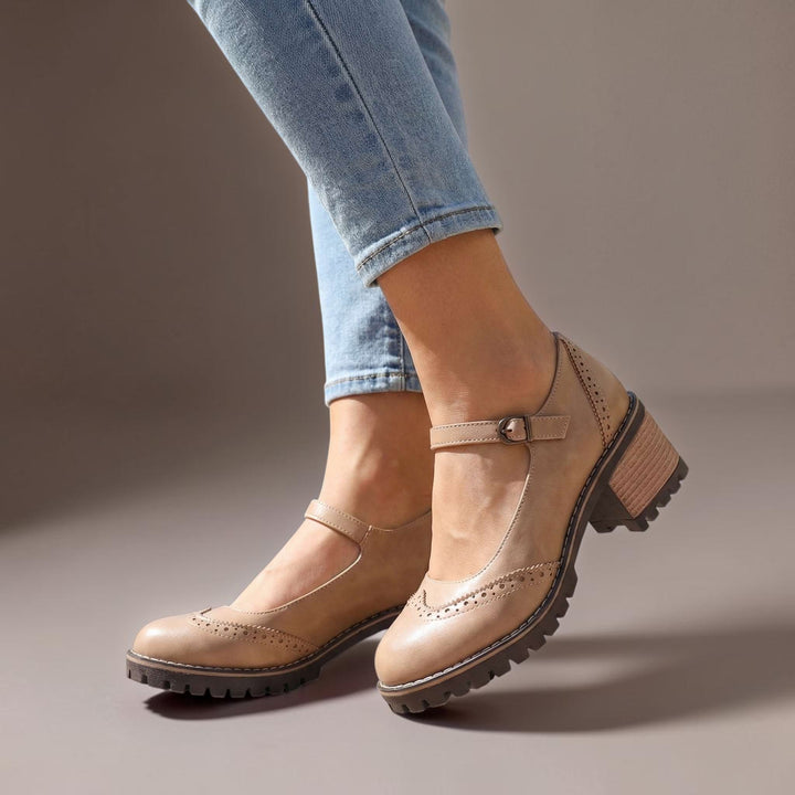 Vivian &amp; Cole khaki Marie T-Strap Mary Jane heels with brogue detailing and a block heel worn with blue jeans.
