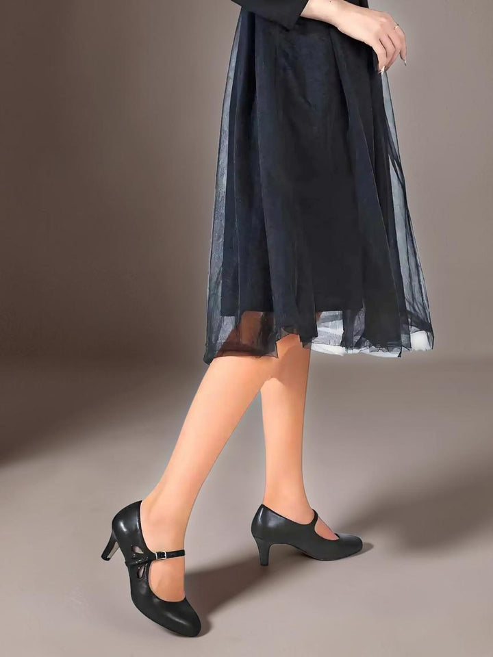 Vivian &amp; Cole Odette classic black office pumps with a manageable heel and ankle strap worn with a black skirt.