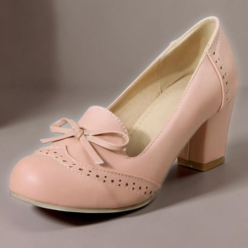 Vivian &amp; Cole Adelaide pink bow slip-on pumps with a block heel and decorative brogue-style perforated detailing.