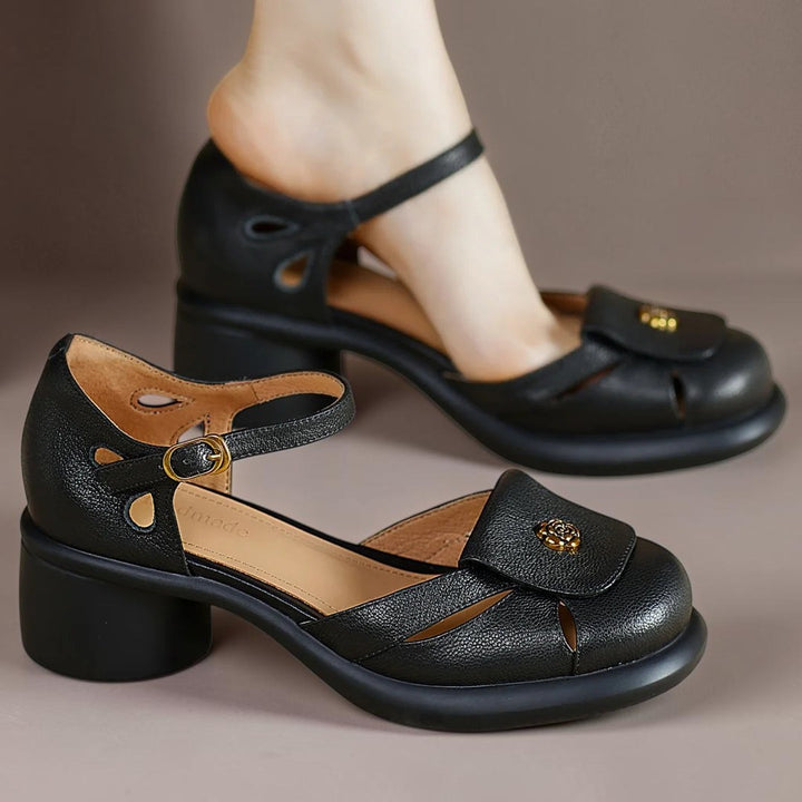 Vivian &amp; Cole Seraphine black leather platform sandals with an adjustable ankle strap and gold floral detail.
